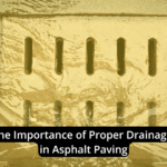 A close-up of a storm drain with water flowing into it, overlaid with the text: "The Importance of Proper Drainage in Asphalt Paving." This highlights how drainage in asphalt is crucial for long-lasting, durable surfaces.